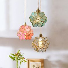 three colorful lights hanging from the ceiling above a table with a potted plant on it