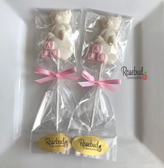 two teddy bear lollipops wrapped in cellophane with pink ribbon and bow