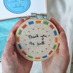 a person holding up a small embroidery hoop with the words thank you, this smith on it