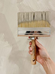 a hand holding a paint brush over a wall