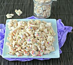 a blue plate topped with sprinkles next to a jar filled with cookies