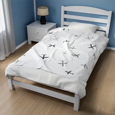 a bed with white sheets and black airplanes on it in a blue room next to a night stand