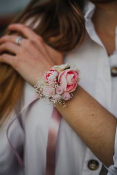 a woman wearing a white shirt and pink flowers on her wrist