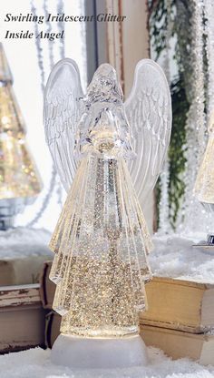 an angel figurine sitting on top of snow covered ground next to a mirror