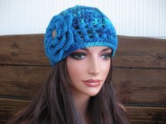 a mannequin head wearing a blue crocheted hat with flowers on it