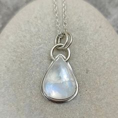 This elegant teardrop shaped Rainbow Moonstone has a fabulous blue flash across its surface when moved.  The stone is set in a Fine Silver bezel and sits on 0.7mm Sterling Silver sheet.  The top loop is made from 1.3mm round Sterling Silver wire and the two bail loops are made from 1mm Sterling Silver wire. The pendant including the bail loops measures 30.5mm x 16mm.   The back plate of the pendant measures 20.5mm x 16mm and the stone measures 18mm x 14mm. All measurements are approximate. The p Teardrop Moonstone Necklace With Birthstone, Blue Teardrop Moonstone Jewelry, Teardrop Blue Moonstone Jewelry, Teardrop Moonstone Gemstone Necklace, Silver Pear-shaped Moonstone Jewelry, Moonstone Teardrop Pendant Jewelry, White Teardrop Jewelry With Moon Charm, Minimalist Teardrop Moon Charm Jewelry, Minimalist Teardrop Jewelry With Moon Charm