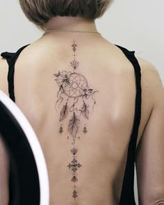 the back of a woman's neck with a dream catcher tattoo design on it