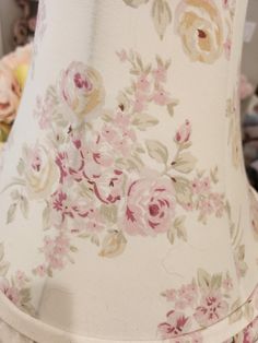 a white lamp with pink and yellow flowers on it next to other lampshades