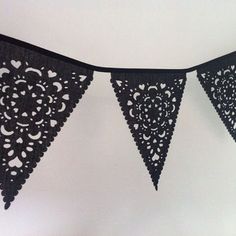 black lace bunting with hearts on it hanging from the ceiling in front of a white wall