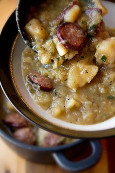 a close up of a bowl of food with meat and potatoes in it on a table