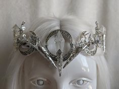 The queen resides in her magical forest and where she reigns, tree branches are made entirely of ice and leaves are made of snow. This unique and beautiful tiara features five clear glass icicles reminiscent of ice, with a triple moon motif decorating the background of the piece. Branches and white leaves surround the piece, creating a gorgeous winter ice queen look. Choose between silver charms as pictured or bronze charms! Choose your crystal color, clear or iridescent! Silver Fantasy Crown Headpiece, Tree Crown, Crystal Crowns, Elf Cosplay, Beautiful Tiaras, Winter Fairy, White Leaves, Homemade Beauty, Triple Moon