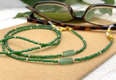 Shiny and bohemian eyeglass necklace chain in green tones with light flashes of gold, made with tiny  Preciosa Czech crystal seed beads and genuine green Jade gemstones.     Paired with beautiful tiny gold plated crystal seed beads, this delicate handmade eyeglass chain will definitely create a unique look. This eyeglass lanyard is made on strong quality beading wire with wire guardians that protect the quality eyeglass holder grips. The necklace is ended with spring clasps that hold the eyeglas Green Beaded Necklace With Adjustable Chain, Elegant Green Glasses Chains For Gift, Green Glass Festival Jewelry, Bohemian Green Glasses Chains, Green Bohemian Glasses Chains As Gift, Green Beaded Glasses Chain As Gift, Green Beaded Glasses Chain Gift, Green Beaded Chain Glasses For Gift, Green Glasses Chains With Round Beads For Gift