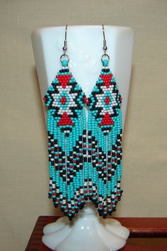 American Indian Motif Earrings, Beaded with 11/0 Round Toho seed beads, these earrings reflect tribal earrings worn by American Indians. They are 4 1/2" from the top of the ear wire, and 1" wide. The earwires are stainless steel 21 gage. The Colors are turquoise, red, black, white. Southwestern Blue Beaded Earrings With Round Beads, Southwestern Green Earrings With Colorful Beads, Southwestern Style Green Earrings With Colorful Beads, Southwestern Green Beaded Dangling Earrings, Southwestern Green Earrings With Dangling Beads, Unique Turquoise Beaded Earrings, Southwestern Turquoise Beaded Earrings, Southwestern Turquoise Earrings With Colorful Beads, Southwestern Style Turquoise Beaded Earrings