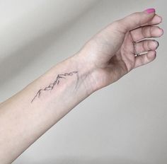 a woman's arm with a small mountain tattoo on the left side of her wrist