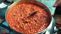 a person stirring beans in a pot on the stove