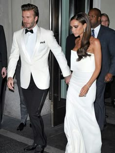 a man in a tuxedo walking next to a woman in a white dress