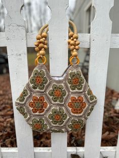 a crocheted purse hanging on a white picket fence