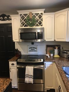 a kitchen with white cabinets and stainless steel stove top oven in the middle of it