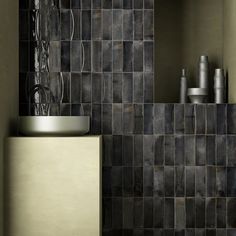 a black tiled bathroom with a sink and mirror