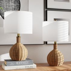 two lamps sitting on top of a wooden table next to a book and lamp shade