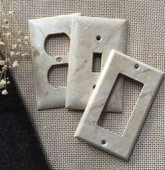 two white switch plates sitting on top of a table next to a vase with flowers