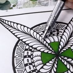 someone is drawing something on the paper with a pen and inking it in green