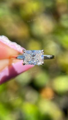 a close up of a person's hand holding a ring with a diamond on it