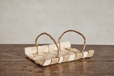 two small baskets sitting on top of a wooden table next to an empty basket with twine handles