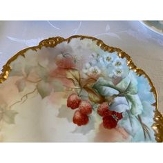 a plate with flowers and berries on it sitting on a white tablecloth covered table