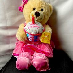 a teddy bear with a birthday cupcake in its mouth