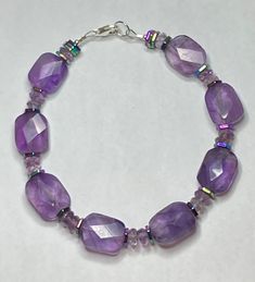 Amethyst Purple Bracelet with Iris Hematite beads * Large High Quality rectangular     faceted Amethyst stones * Amethyst roundel beads * Iris Hematite stone multi toned     hexagon beads * Sterling Silver Lobster claw clasp * Lg. sterling silver O ring for easily     attaching clasp.  * Makes a great gift for your mom,     wife, sister or daughter. Faceted Amethyst Gemstones For Jewelry Making, Adjustable Amethyst Rondelle Beaded Bracelets, Faceted Amethyst Beads, Faceted Round Amethyst Beads, Purple Gemstone Beads, Purple Round Gemstone Beads, Round Faceted Amethyst Beads, Purple Rondelle Beaded Gemstone Bracelets, Amethyst Beaded Bracelets With Faceted Beads