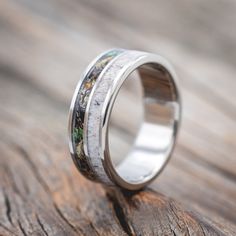 a wedding band with moss and silver inlays on top of a piece of wood