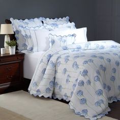 a bed with blue flowers on it in a bedroom next to a night stand and nightstand