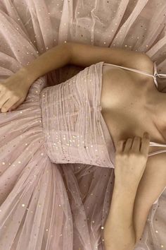 a woman laying on top of a bed in a pink dress with gold glitters