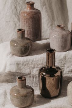 several different vases sitting on top of a white cloth