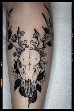 a black and white photo of a deer skull with flowers on it's side