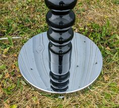 a black and silver object sitting on top of a metal plate in the middle of grass