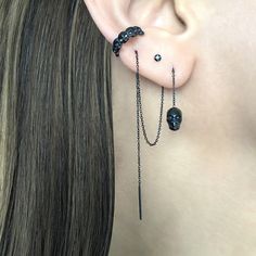 a woman wearing black ear piercings with chains and skulls on them