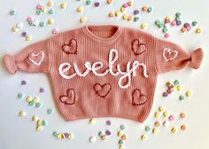 a pink sweater with hearts and the words evelyn on it surrounded by sprinkles