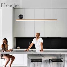 a man and woman sitting at a kitchen counter with stools in front of them