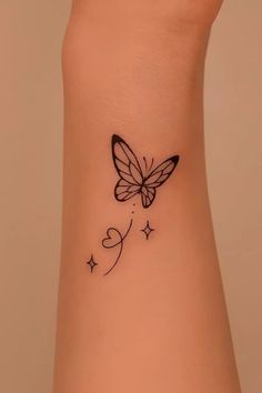 a small butterfly tattoo on the side of a woman's arm, with stars and hearts