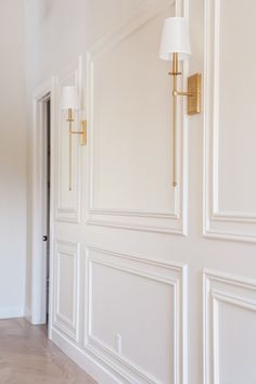 an empty room with white walls and gold trim on the door, light fixture and floor lamp