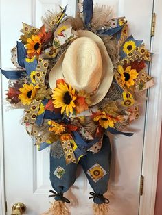 a scarecrow door hanger decorated with sunflowers, feathers and a cowboy hat