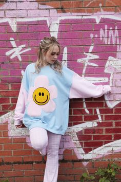 The Happy Flower Jumper! A Blue bodice complete with large Pink Fleece Flower and Yellow Chenille Smiley Face for the centre. Hand sewn on with playful thick thread. Pink Sleeves!! What a great addition to your weird and wonderful Wardrobe. Bringing lots of happy happy vibes! Very 90s!  STYLING TIPS: Looks great matched with Denim Jeans and Trainers. Have the coolest hangover Sweatshirt at a Festival or chuck it on down at the beach. So many fun styling options with this one.  SIZING GUIDE: Can 90s Pastel Fashion, Playful Spring Sweatshirt For Loungewear, Playful Spring Loungewear Sweatshirt, Light Blue Sweatshirt For Spring Loungewear, Blue Oversized Sweatshirt For Spring, Oversized Blue Sweatshirt For Spring, Cute Oversized Blue Tops, Playful Crew Neck Sweatshirt For Spring, Oversized Patchwork Sweatshirt For Spring