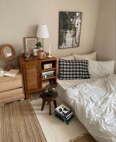 a bed with white sheets and pillows next to a wooden cabinet filled with books on top of it