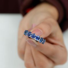 a woman's hand holding a ring with blue sapphires on the inside of it