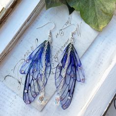 Our very pretty purple faerie wing earrings which are just perfect for any faerie! We make the wings ourselves and they are made from a type of plastic and magic, oh and a sprinkle of glitter of course! The two wings are separate which help create movement Finished with the best quality crystals and a pretty crystal drop, which catches the light perfectly! We make the wings ourselves and they are made from a type of plastic and magic, oh and a sprinkle of glitter of course! The two wings are separate which help create movement. We offer these earrings in sliver plated and bronze plated nickel free earring hooks Please note that no faeries have been harmed in the making of these wings! Villainous Outfits, Vibey Jewelry, Purple Fairycore Jewelry For Party, Blue Fairy Jewelry For Party, Blue Fairy-style Jewelry For Party, Knight Cookie, Tvd Dr, Wing Jewelry, Fairy Jewelry