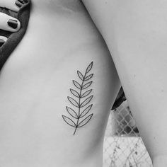 a black and white photo of a woman's stomach with a leaf tattoo on it