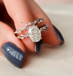 a woman's hand holding a ring with a diamond on it and blue nail polish