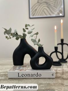 two black vases sitting on top of a table